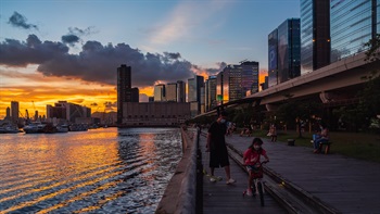 A bike ride along the promenade provides sweeping views of the harbour under a golden blue sky at sunset.